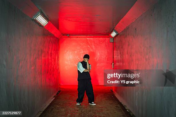a photo of a dancer posing in an underground passageway, lit by colored strobe lights. the dancer is a young asian man. - gangsta rap photos et images de collection