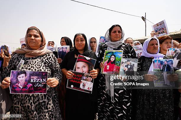 Iraqi Yazidi women hold pictures of their victims and missing relatives during a ceremony at Chamishko camp for Yazidi IDPs, in the Kurdistan Region...
