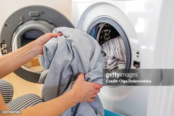putting laundry into a washing machine - bedclothes stock pictures, royalty-free photos & images