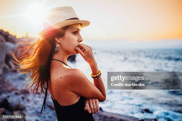 donna in riva al mare che fissa il tramonto - guardare fisso foto e immagini stock