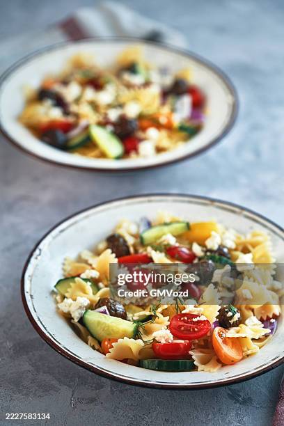 greek salad with farfalle pasta, tomato, cucumber, bell pepper, olives and feta cheese - greek salad stock pictures, royalty-free photos & images