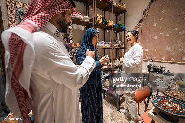 couple arabe et femme dans une boutique d’art traditionnel à al balad - culture saoudienne photos et images de collection