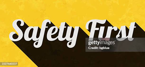 safety first - text with long shadow on textured yellow background - safety first stock illustrations