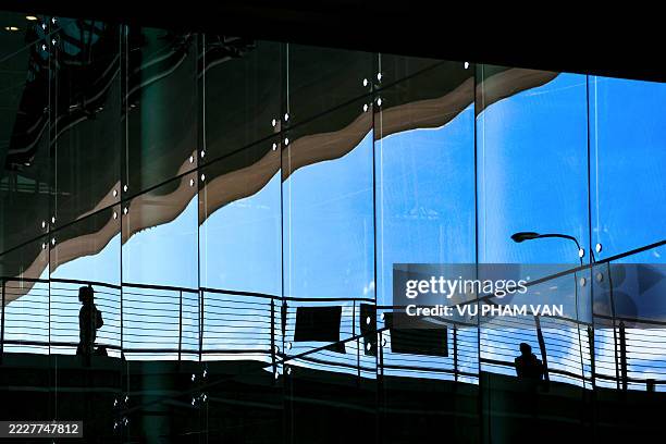 passengers on elevated skywalk reflected on glass wall - midday stock pictures, royalty-free photos & images