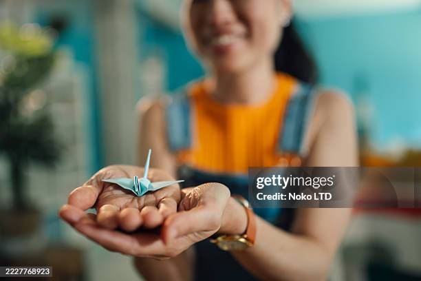 woman showing origami crane in her hands - origami stockfoto's en -beelden