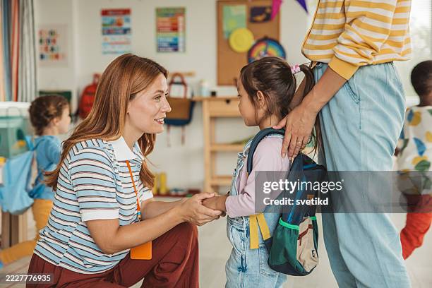 preschool teacher in classroom greeting new student - preschool stock pictures, royalty-free photos & images