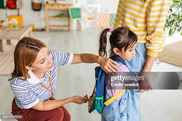 preschool teacher in classroom greeting new student - tímido imagens e fotografias de stock