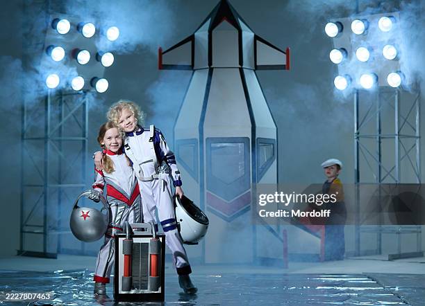 two cheerful girls astronauts standing embracing, smiling, looking at camera - spaceport stock pictures, royalty-free photos & images