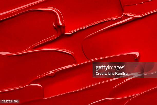 vivid close-up of red lipstick texture with smooth, flowing strokes, smears. bold and luxurious beauty background, perfect for cosmetics, makeup, and skincare concepts. abstract and richly detailed. - maquilhagem imagens e fotografias de stock