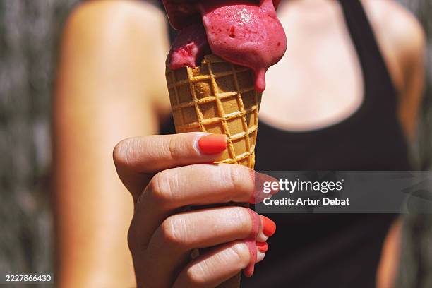 close-up of a teenager enjoying ice cream cone melting in her hand on a hot summer day - girl eating messy ice cream cone stock-fotos und bilder