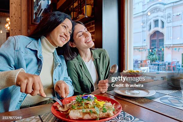 two happy young women enjoying a healthy meal at a restaurant - brunch stock pictures, royalty-free photos & images
