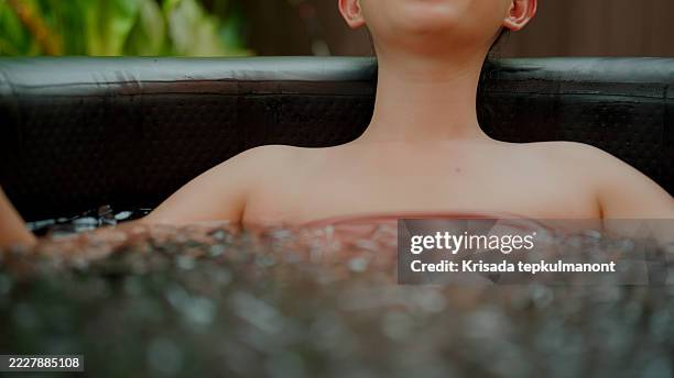 junge asiatische frau lächelt, während sie sich in einer eisbadtherapie entspannt. - den sprung wagen stock-fotos und bilder