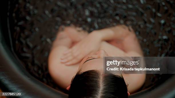 junge asiatische frau, die meditiert, während sie eine eisbadtherapie hat. - den sprung wagen stock-fotos und bilder