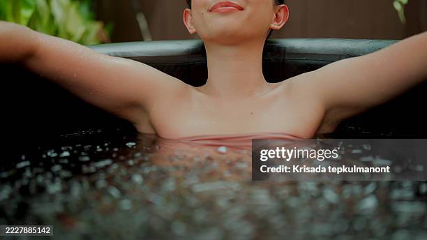 junge asiatische frau lächelt, während sie sich in einer eisbadtherapie entspannt. - den sprung wagen stock-fotos und bilder
