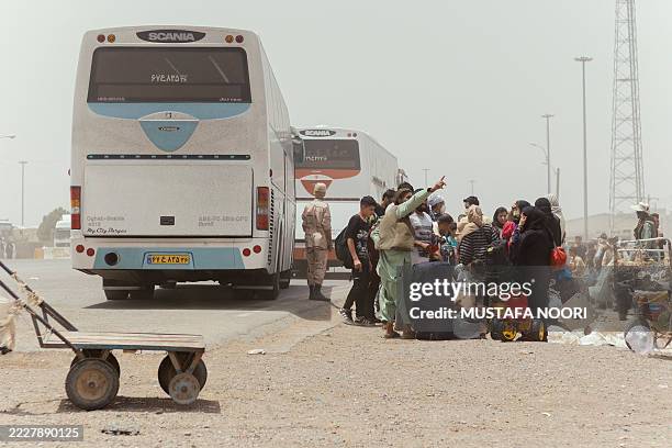 Recently deported Afghans walk between parked buses and scattered belongings at the Islam Qala border crossing in Herat, Afghanistan, July 2, 2025....