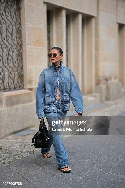 Sophia Geiss is seen wearing a mid blue oversized denim shacket with faded detailing, flap and patch pockets and high collar, only closed with two...