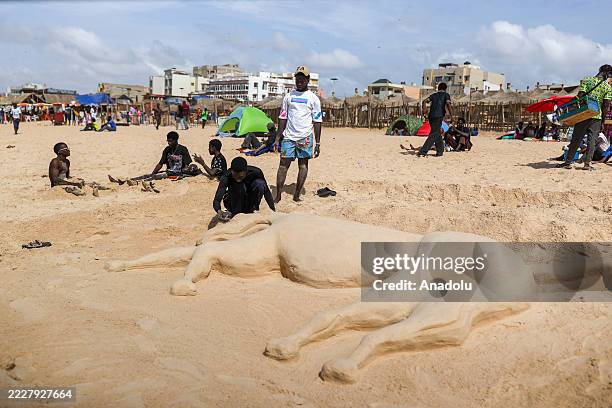 Sand sculptor Omar Mbaw, a 27-year-old tailor from the Yoff neighborhood, creates sand sculptures on various beaches in Dakar, where he seeks...