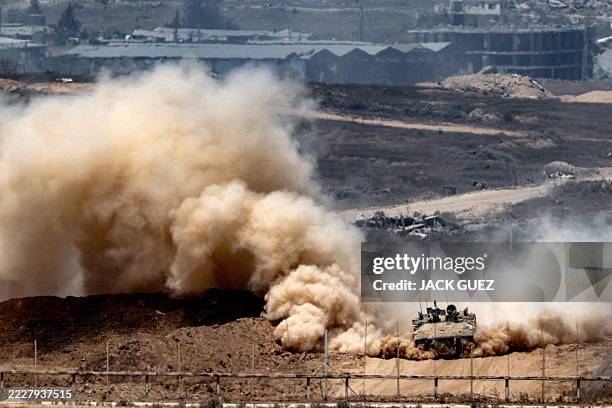 An Israeli army infantry-fighting vehicle leaves a cloud of dust as it moves at a position along Israel's southern border with the Gaza Strip on...