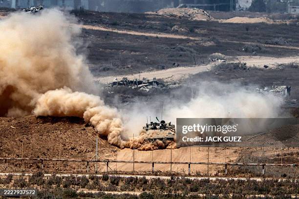 An Israeli army infantry-fighting vehicle leaves a cloud of dust as it moves at a position along Israel's southern border with the Gaza Strip on...