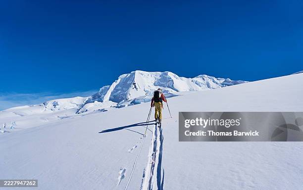 wide shot backcountry ski guide leading group up mountain in antarctica - scialpinismo foto e immagini stock