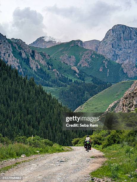 cyclist exploring tian shan mountains in kyrgyzstan - montañas de tien shan fotografías e imágenes de stock