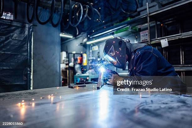 soldador trabajando con un soplete de soldadura en una fábrica de bicicletas - soldar fotografías e imágenes de stock