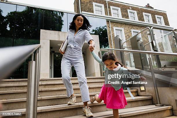 mother and daughter running down the school stairs holding hands - kids running down stairs photos et images de collection