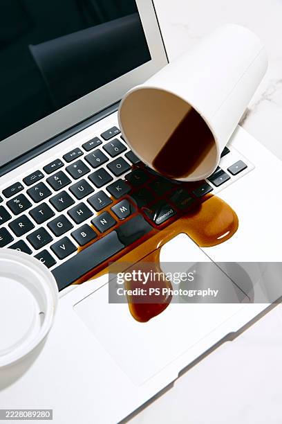 spilled coffee on a laptop - knoeien stockfoto's en -beelden