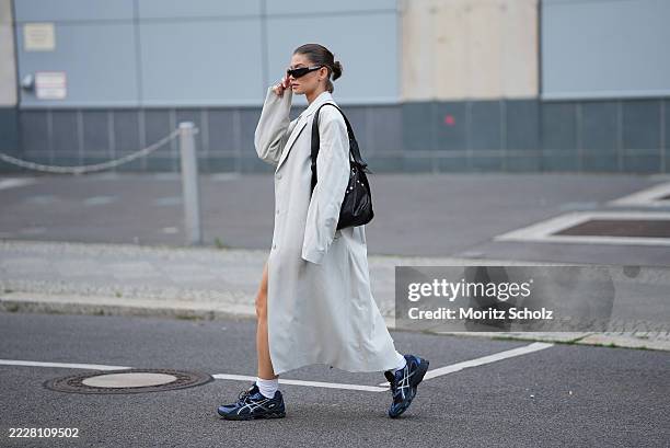 Sophia Geiss is seen wearing a light grey extra long oversized Tribeca coat with padded shoulders and notch lapels from The Frankie Shop; a light...