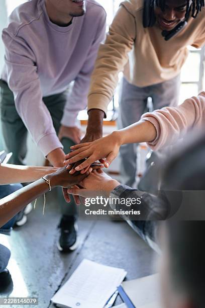 group of students joining hands in a classroom setting for a team bonding activity - continuous learning stock pictures, royalty-free photos & images
