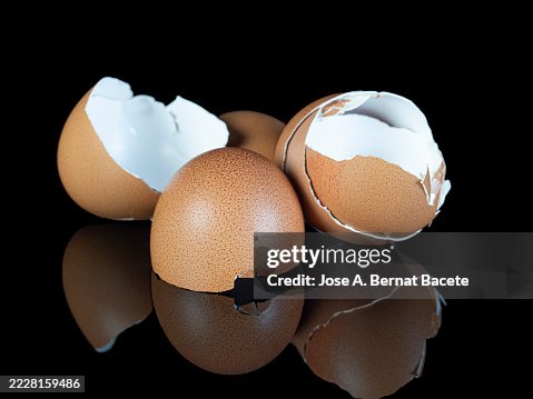 Three broken chicken eggshells, reflected on a black background. Three broken chicken eggshells, reflected on a black background.