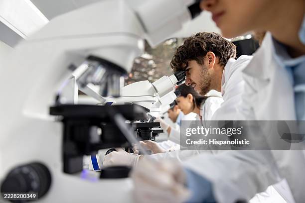 medical student looking through a microscope at the laboratory - wetenschappelijk onderzoek stockfoto's en -beelden