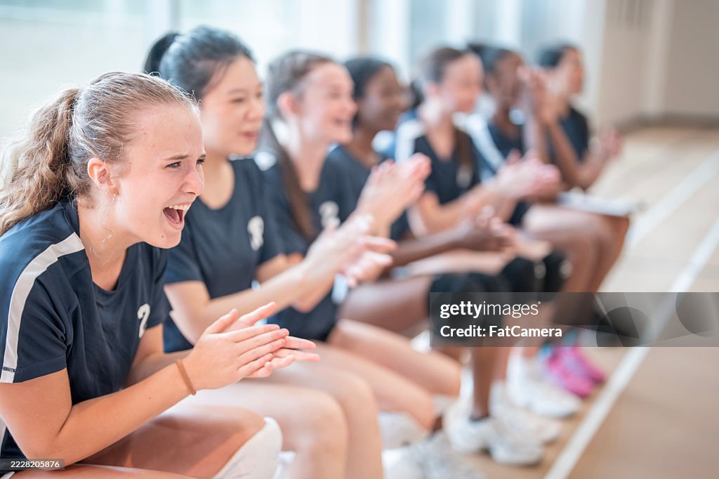 Excited Female Volleyball Team Cheering During Match on Indoor Court