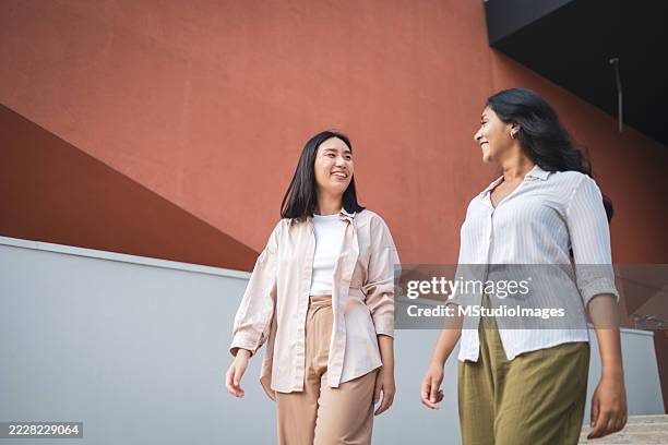 two young businesswomen walking and talking outside office - indian fashion show stock pictures, royalty-free photos & images