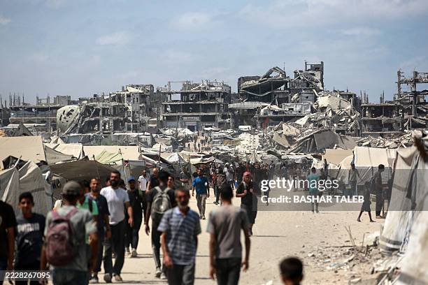 Palestinians walk along a street near war-damaged buildings in Gaza City on August 8, 2025. Israel's military will "take control" of Gaza City under...