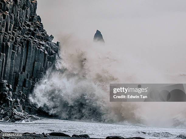 olas dramáticas rompiendo contra acantilados de basalto en islandia - columna de basalto fotografías e imágenes de stock
