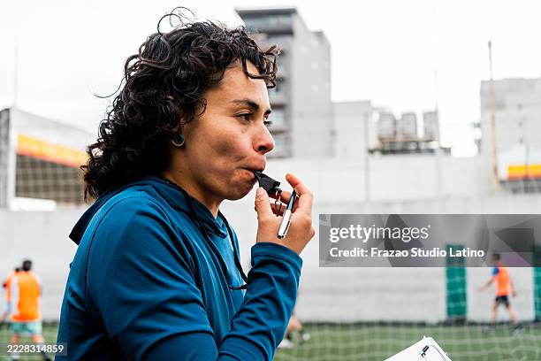 female coach using whistle during a football match on the field - referee blowing whistle stock pictures, royalty-free photos & images
