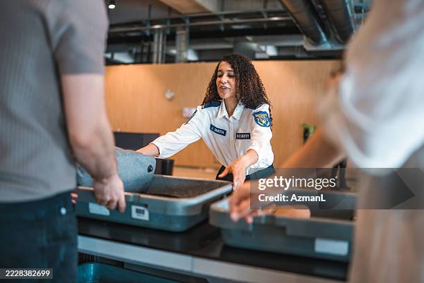 hispanic female security officer in white uniform checking passenger luggage at airport screening point - security staff stock pictures, royalty-free photos & images
