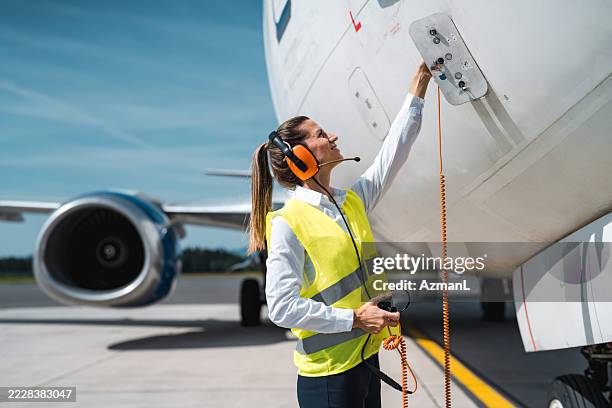 caucasian female ramp agent plugging headset into aircraft panel - airfield stock pictures, royalty-free photos & images
