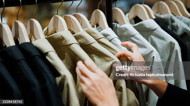un homme parcourt des sélections de vêtements sur un présentoir tout en faisant ses courses dans un centre commercial. - industrie de la mode photos et images de collection