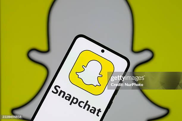 The Snapchat logo is displayed on a mobile phone with the Snapchat icon in the background in this photo illustration in Brussels, Belgium, on August...