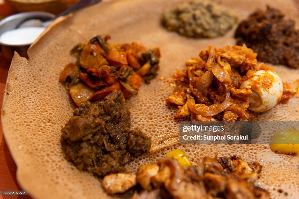 An Ethiopian dish featuring various seasoned meats is served atop sourdough flatbread, known as injera, for communal eating. Ethiopia.