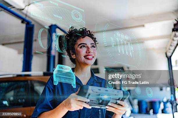 young mechanic woman using scanner and analyzing data on augmented reality at auto repair shop - augmented reality car stock pictures, royalty-free photos & images