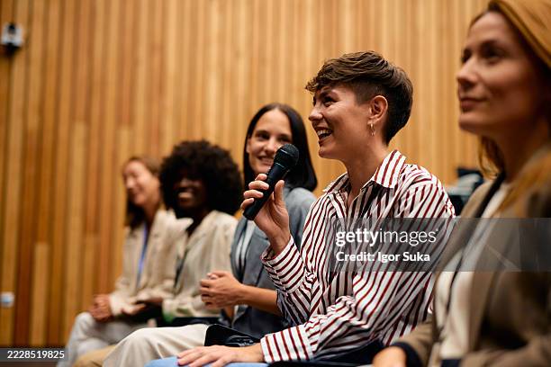 businesswoman speaking at a conference using a microphone - audiência imagens e fotografias de stock