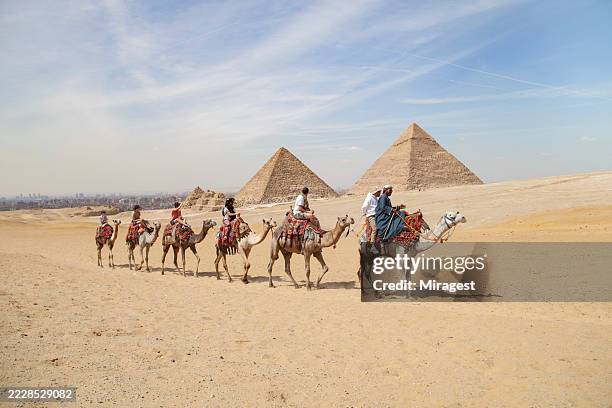 tourists riding camel in the egyptian desert and visits the pyramids in cairo. - small group of people stock pictures, royalty-free photos & images