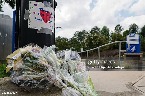 Flowers are seen below a handwritten sign outside the Centers For Disease Control Global Headquarters following a shooting that left two dead, on...