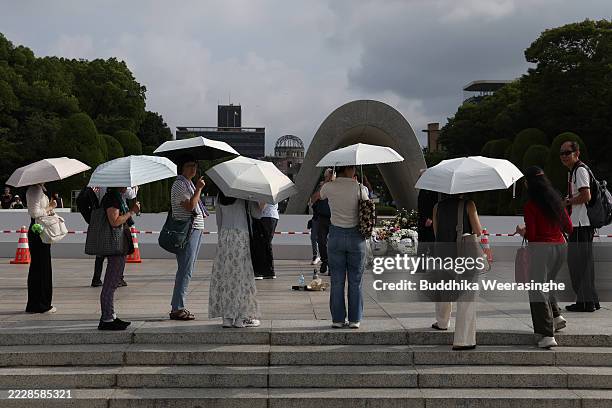 Visitors use umbrellas to get relief from the sun during the extremely hot day ahead of the 80th anniversary of the atomic bomb dropped on Hiroshima...