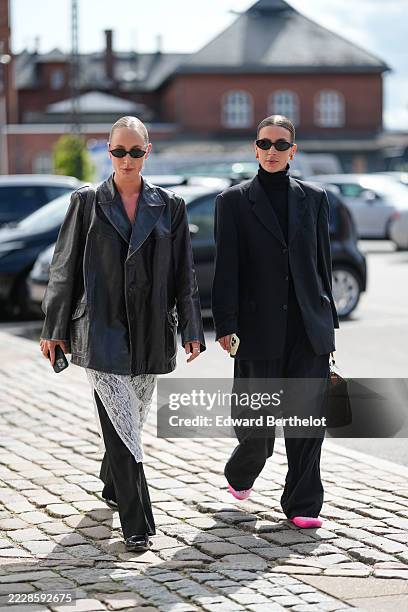 Guest wears a black leather oversized blazer over a white lace dress with intricate floral patterns. Black straight-leg trousers are visible...