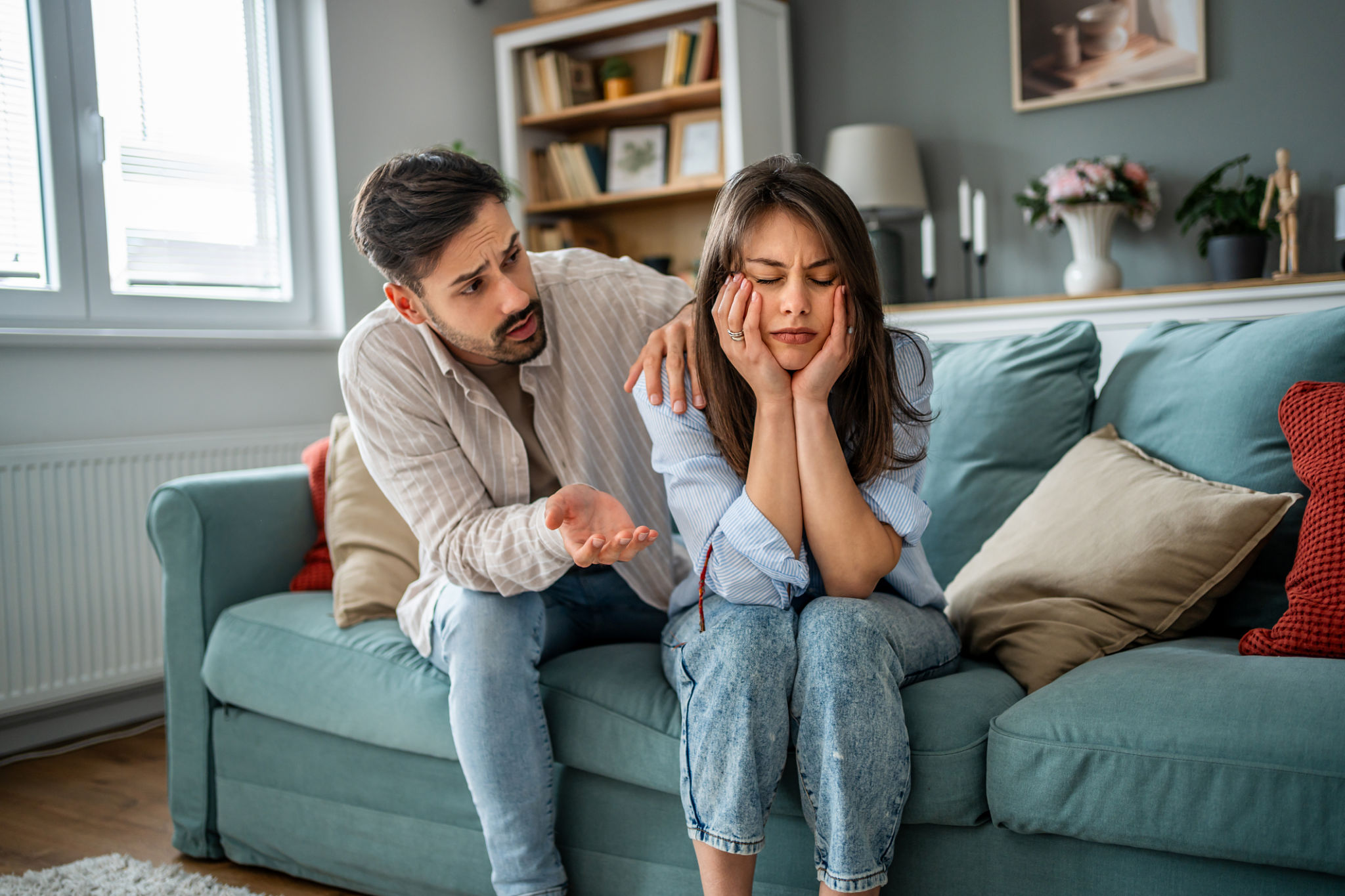 Young man comforting sad girlfriend at home on sofa Young man comforting sad girlfriend at home on sofa