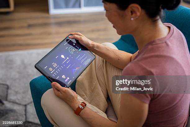 woman using smart home control app on a digital tablet - home automation stock pictures, royalty-free photos & images